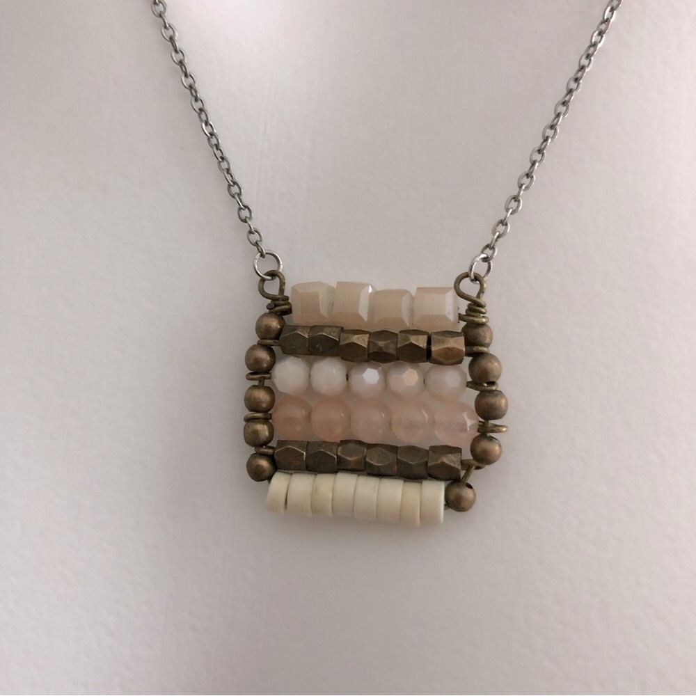 Silver fashion necklace with square pendant featuring various shaped beads.